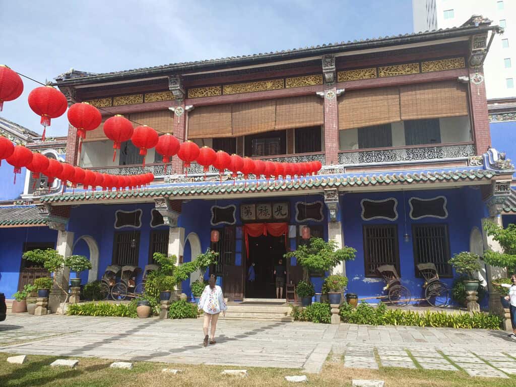 The Cheong Fatt Tze Mansion in George Town, Penang, also known as the Blue Mansion, with its vibrant blue walls, traditional Chinese architectural details, and strings of red lanterns hanging across the courtyard.