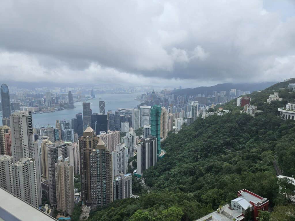 A wide view of Hong Kong Island’s dramatic contrast between forested hillsides and modern high-rises stretching along Victoria Harbour, taken from an elevated lookout.
