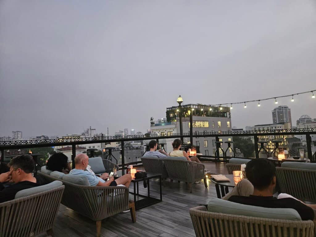 Guests relaxing on a rooftop terrace at Solaria Hotel Hanoi with city skyline views at dusk, showing the social atmosphere and views when deciding where to stay in Hanoi.