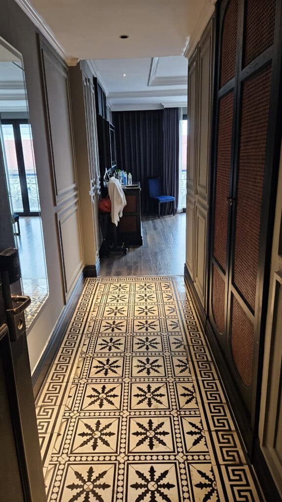 Entrance hallway of a Solaria Hotel Hanoi room featuring patterned tile flooring, wardrobe storage, and a view into the bedroom, showing practical layout details for where to stay in Hanoi.