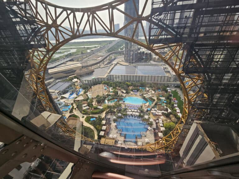 View through the Golden Reel structure at Studio City Macau overlooking resort pools and Cotai below.