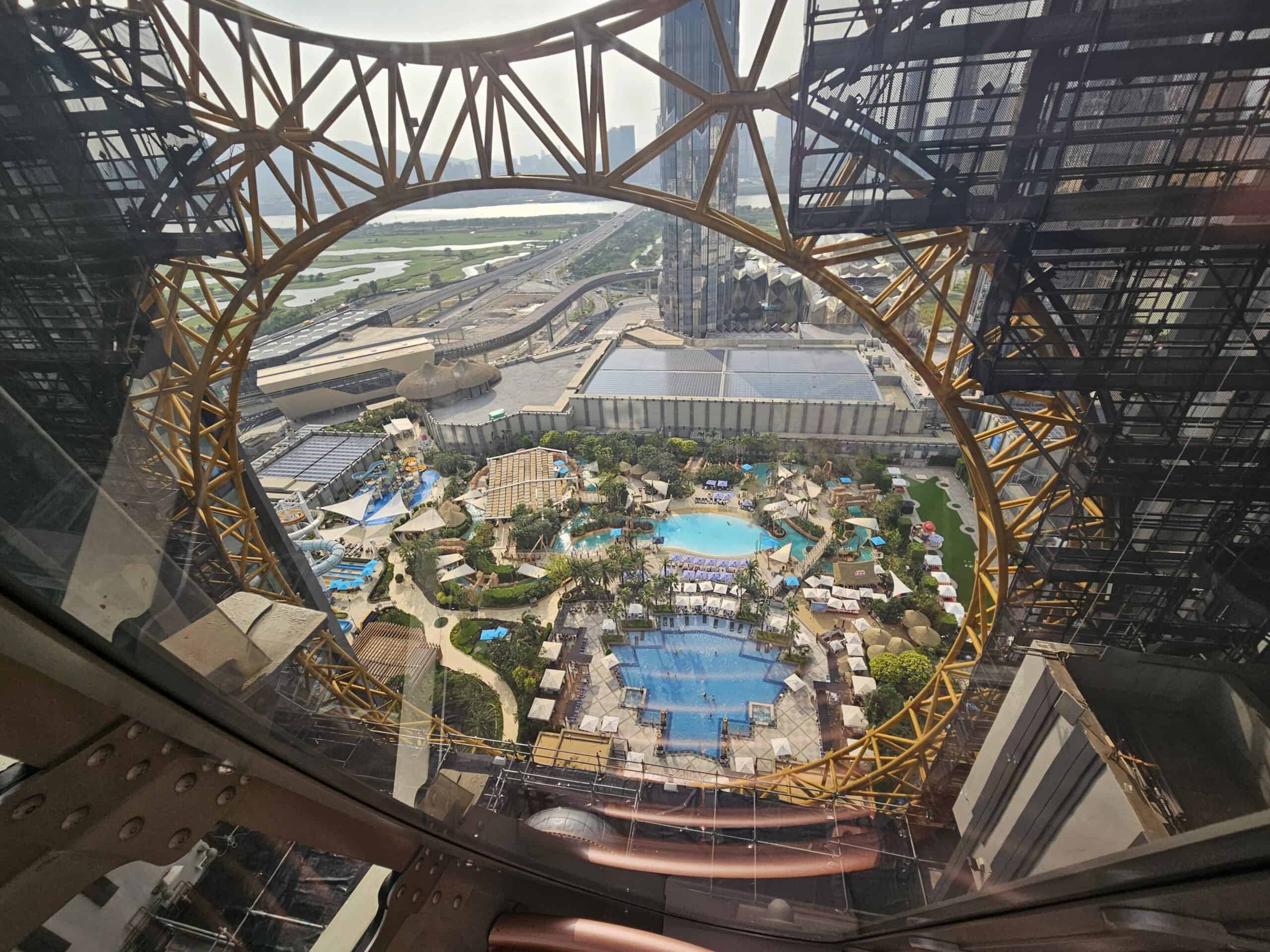 View through the Golden Reel structure at Studio City Macau overlooking resort pools and Cotai below.